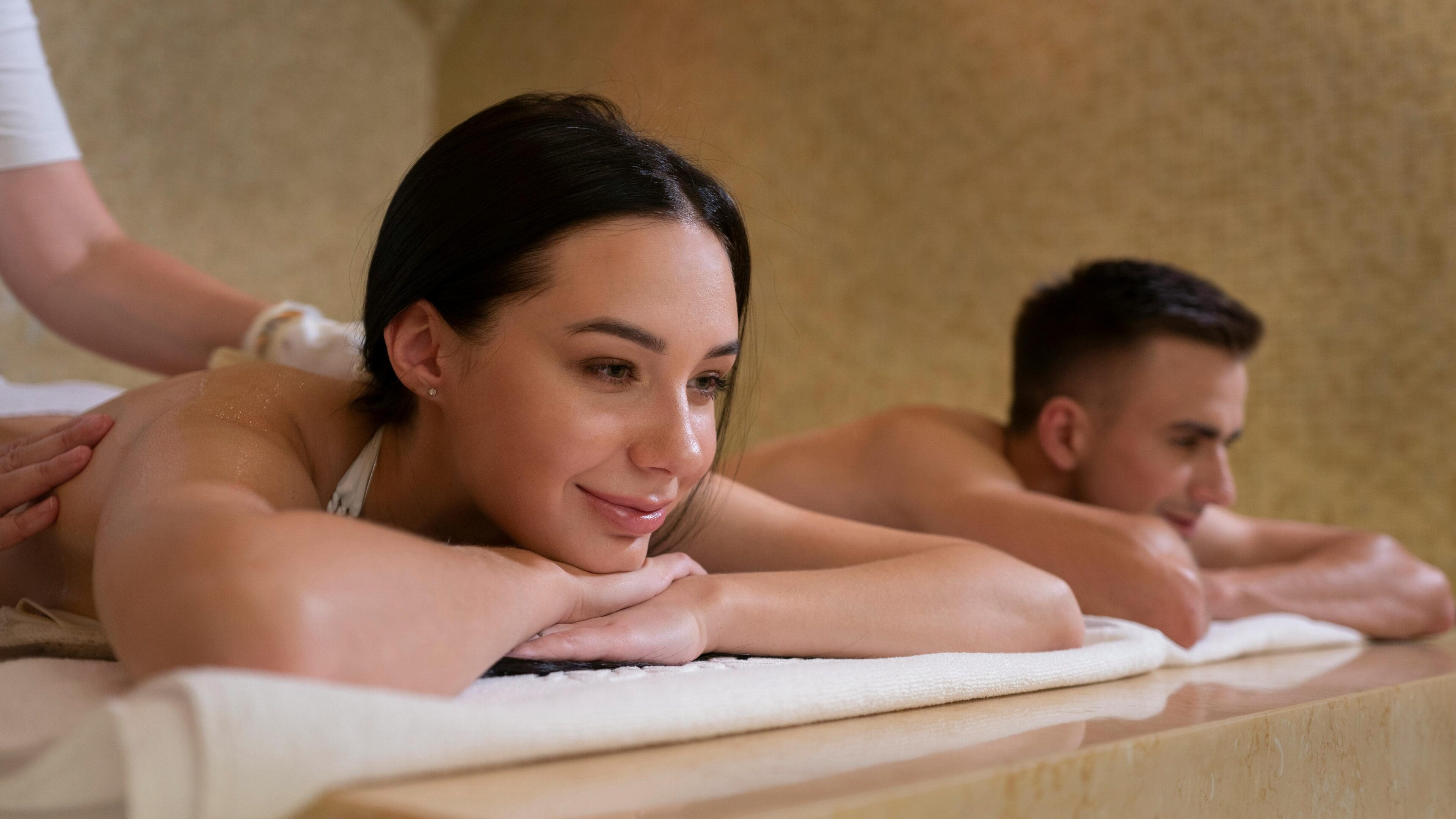 A woman and man laying on towels in a spa.